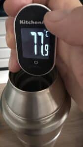 Garrafa térmica mantém café quente por 24 horas? Testei por 33 horas 7 Termômetro digital marcando 77,9 °C na segunda garrafa térmica após uma hora, evidenciando a falha de vácuo