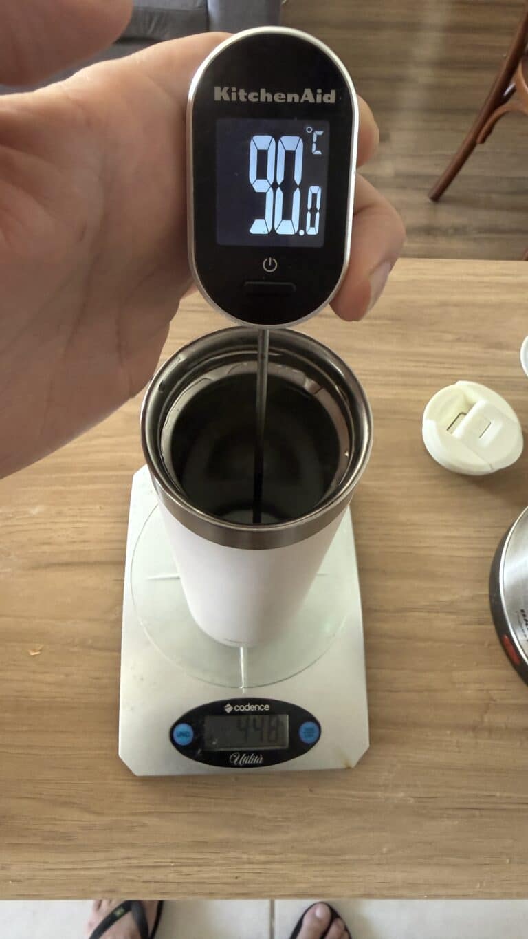 Garrafa térmica pequena para café: medi a Stanley por 24 horas 1 Termômetro digital marcando 90,8 °C dentro da Stanley Aerolight, apoiada numa balança que mostra 448 g de água
